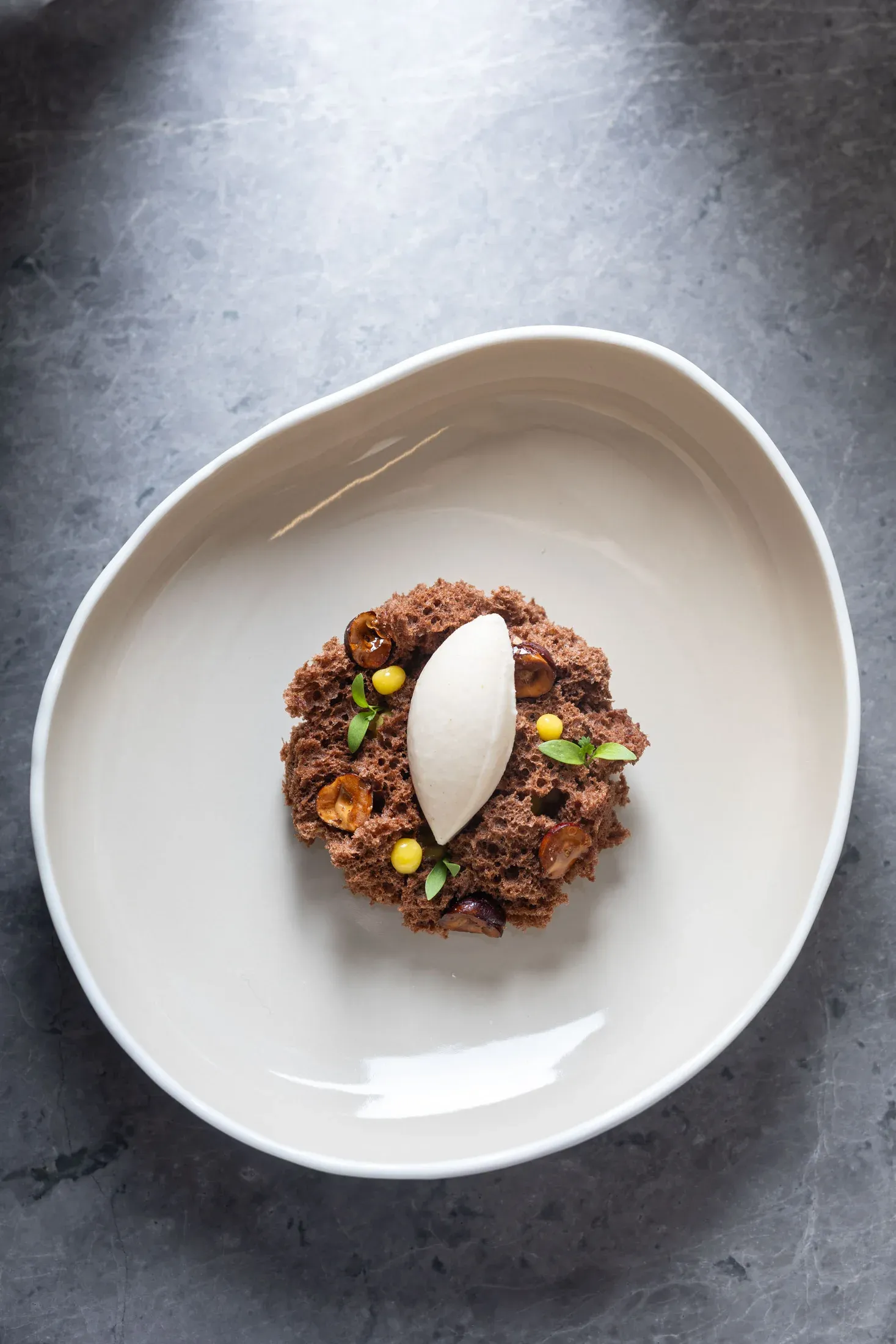 Postre de la casa con crumble de chocolate y una quenelle de helado